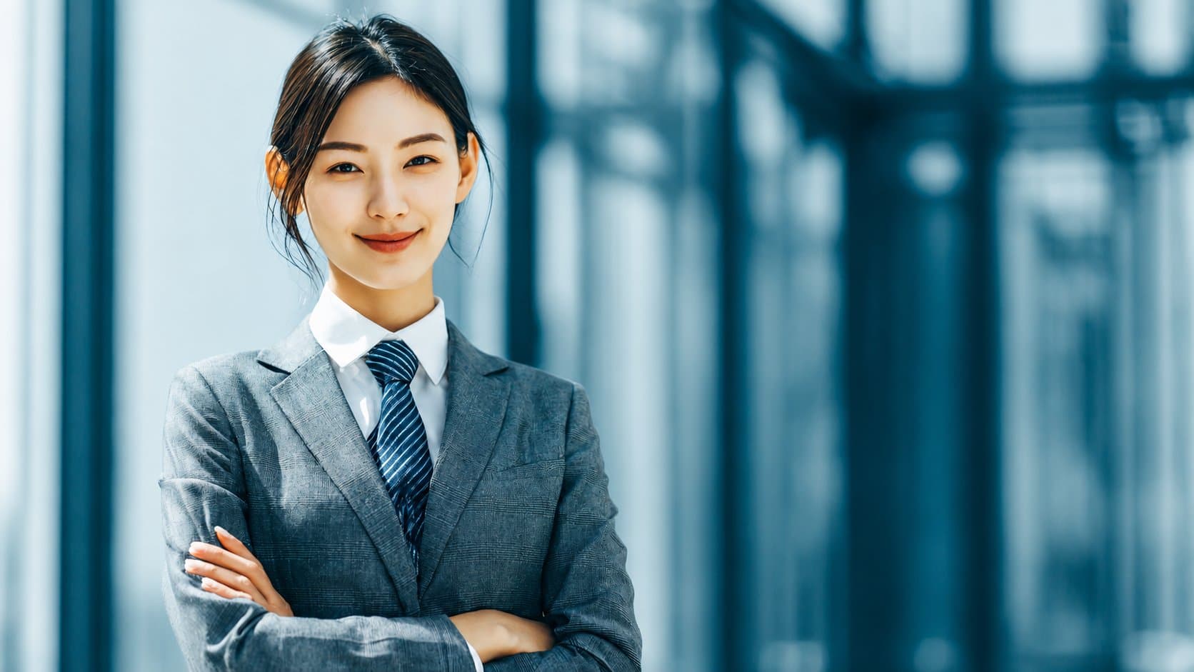 專業的客服人員身著套裝,自信地站在現代化辦公大樓內